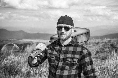 Gitarlı yürüyüşçü güzel manzaraya bakıyor. Kamp tatili. Dağlarda hippi yürüyüşçüyüm. Kendine güvenen bir adamın portresi.