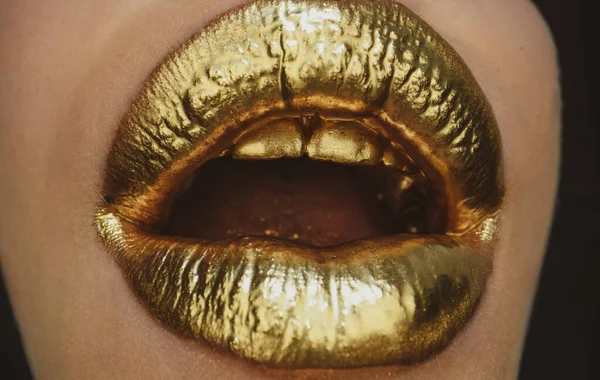 Gouden lippen. Gouden verf uit de open mond. Gouden lippen op vrouwenmond met make-up. Sensueel en creatief design voor gouden metallic. — Stockfoto