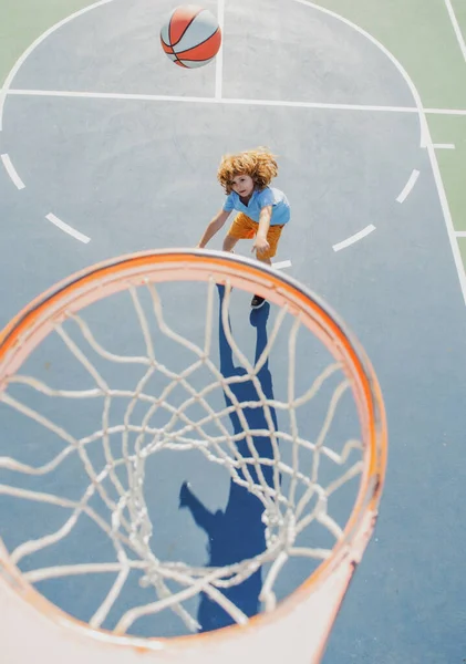 Criança em salto uniforme de basquete com bola de cesta para tiro na quadra de basquete. — Fotografia de Stock