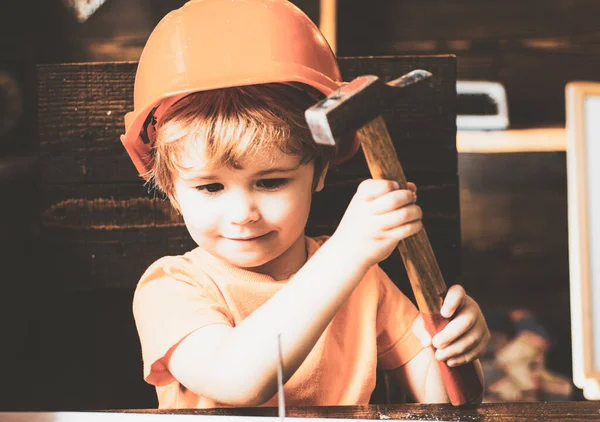Le petit garçon avec un marteau fait des réparations. L'enfant participe activement à un processus artisanal. — Photo