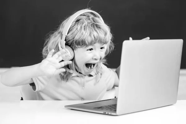 Leuke jongen met koptelefoon, studeren met laptop in de klas, audio les luisteren. Opgewonden verbaasde kinderen emoties. — Stockfoto