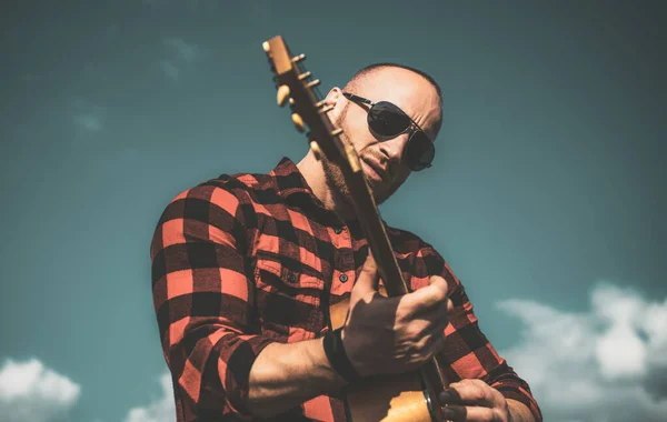 Man wearing sunglasses and playing guitar on sky. Camping holiday. — Stock Photo, Image