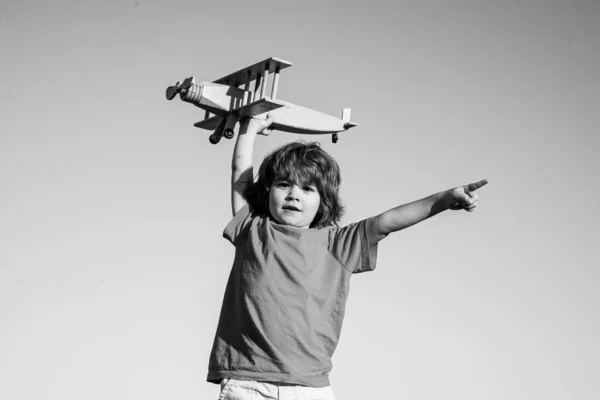 显示或指向复制空间的儿童飞行员。带着木制飞机的小男孩空中有飞机的男孩，天空背景. — 图库照片