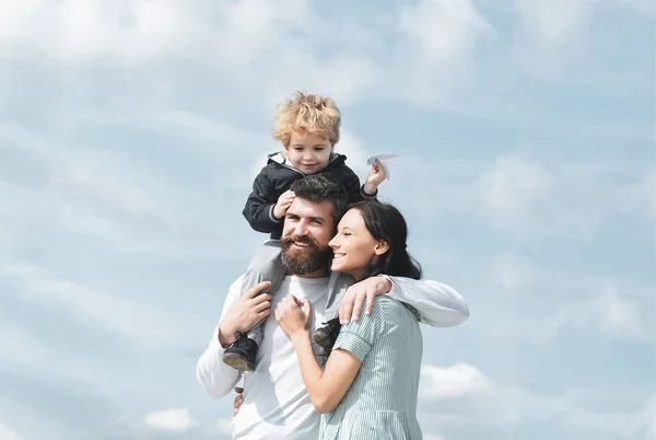Šťastná rodinná matka, otec a syn na nebesích v létě. Dítě sedí na ramenou svého otce. Představivost. — Stock fotografie