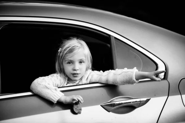 Niña mira por la ventana en el coche y algo muestra una mano . —  Fotos de Stock
