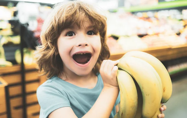 Portrét dítěte při nakupování v supermarketu, nakupování čerstvých banánů v supermarketu. — Stock fotografie