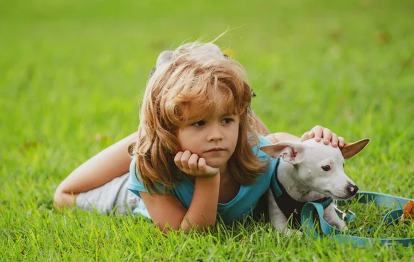 Boy lying on grass with dog. Happy puppy owner child playing with doggy on lawn. — Stock Photo, Image
