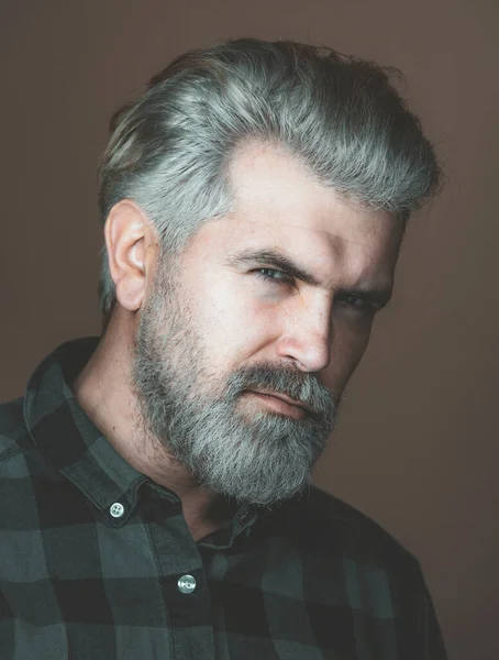 Mature blonde bearded guy with trendy hairdo in casual shirt smiling and looking in camera. Close up portrait of a very handsome man.