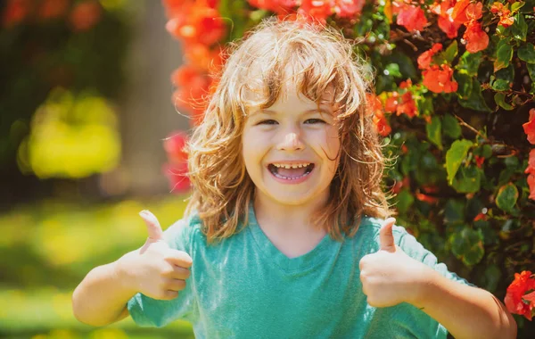 Retrato de uma criança feliz rindo. Fechar o rosto positivo crianças, polegares para cima sinal. — Fotografia de Stock
