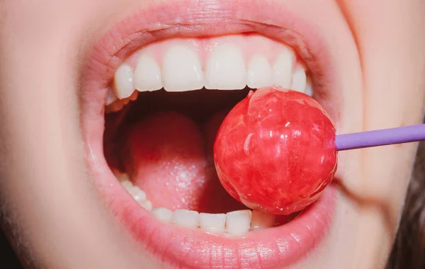 Sexy red lips with candy for print. Red sweet lollipop in the mouth in art design. Glossy womans lips licking sucking lollipop. Sensual sexy mouth with candy concept enjoyment beautiful female lips.