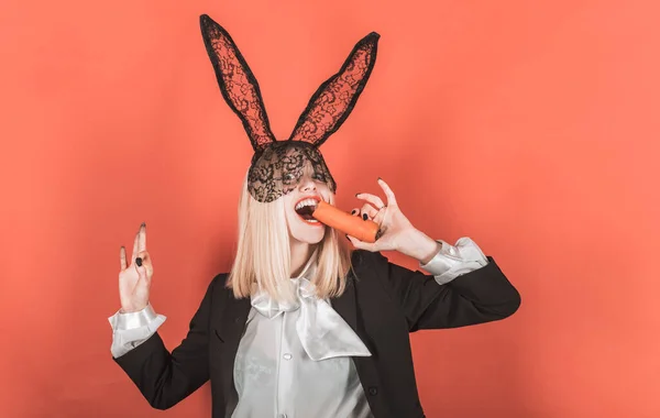 Celebración de Pascua. Mujer sensual con encaje negro orejas de conejo de Pascua con zanahoria. Sexy conejito de Pascua comiendo zanahoria. La Pascua es una fiesta de diversión y alegría de la vida — Foto de Stock