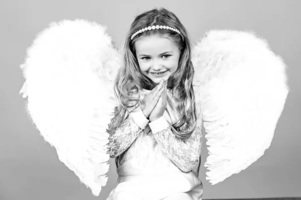 Bella bambina angelo in piedi con le braccia vicino al petto come in preghiera. Angeli mani piccole incrociate per voi. Malizioso piccolo angelo ragazza in piedi con i pugni stretti . — Foto Stock