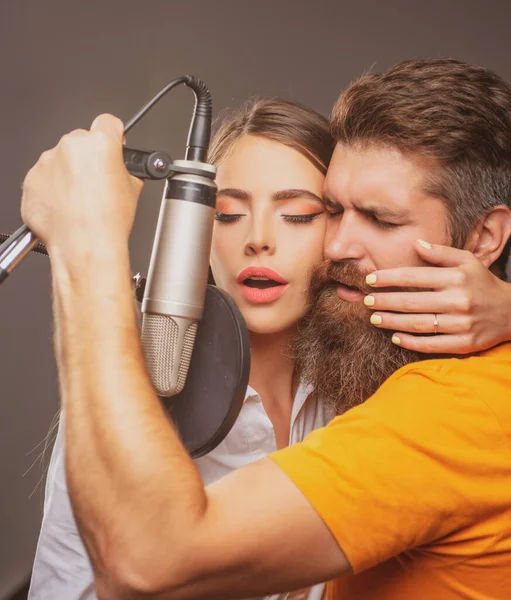Éneklő férfi és nő egy stúdióban. Érzéki pár mikrofonnal. Karaoke énekes, zenei énekes. — Stock Fotó