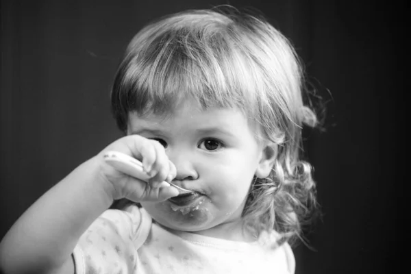 Дитина їсть з брудним обличчям. Весела усміхнена дитина їсть себе з ложкою Дитина їсть з брудним обличчям. Посміхаючись маленькій дитині їсти їжу на кухні. Кід голодний . — стокове фото