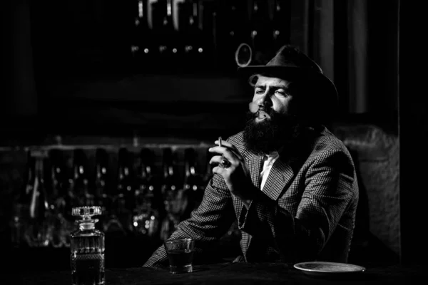 Привлекательный мужчина курит сигареты со стаканом виски. — стоковое фото