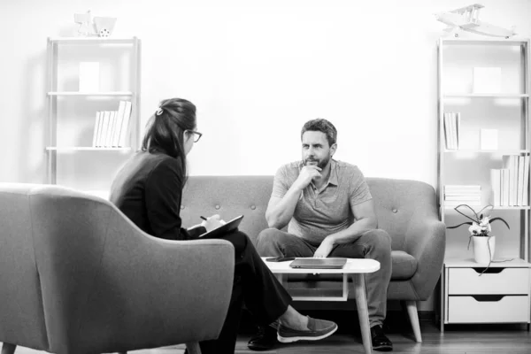 中年男性問題療法.ハンサムな男がソファに座って心理学者と話している。心理学の患者は心理的な相談の間に彼女の精神的な健康について話している. — ストック写真