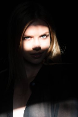 Stüdyoda poz veren genç bir kadın. Işık ve gölge. Yüzünde koyu renk ışık olan güzel bir kadının moda portresi. Kadınların yüzüne gölge ve ışık yansıtan yaratıcı portreler, gözler