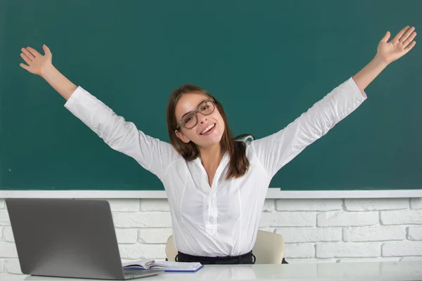 Porträt einer jungen, aufgeregten Schülerin mit erhobenen Händen im Klassenzimmer. — Stockfoto