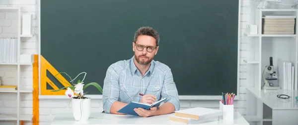 Joven profesor masculino moderno esperando a los estudiantes. Profesor en ropa casual en pizarra con espacio de copia en clase en la escuela. — Foto de Stock
