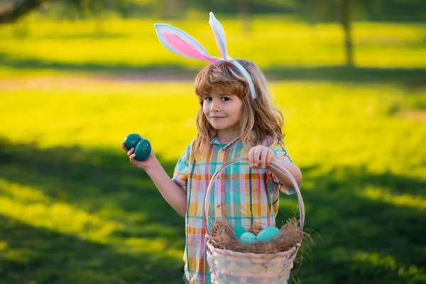 Conejito. Niño con traje de conejo con orejas de conejo cazando huevos de Pascua en el parque. —  Fotos de Stock