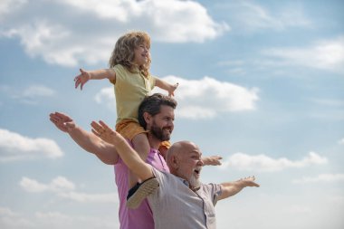 Çocuklarla aktif aile eğlencesi. Oğlu babası ve dedesi olan çocuk el kaldırıyor ya da yaz mevsiminde gökyüzünde uçan kollarını açıyor. Başlangıç, yaratıcılık başlangıç konsepti.