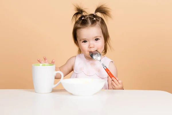 Bebé comiendo comida. Buen apetito. Bebé con cuchara en el estudio, aislado en amarillo beige. — Foto de Stock