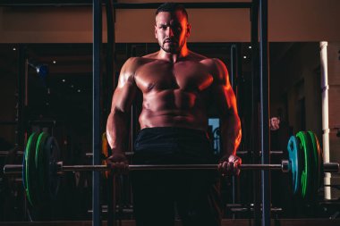 Halter kaldıran kaslı adam. Kaslı ve güçlü adam egzersiz yapıyor. Sporcu ağırlıklarla egzersiz yapıyor. Fitness ve Crossfit.