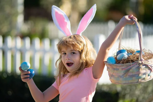 Niño cazando huevos de Pascua. Niña emocionada con canasta de Pascua. Lindo niño en traje de conejo con orejas de conejo teniendo pascua. —  Fotos de Stock