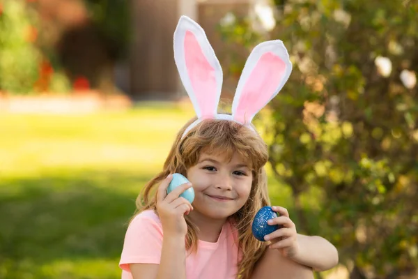 Felices fiestas de Pascua. Niño cazando huevos de Pascua. Niño con huevos de Pascua y orejas de conejo al aire libre. —  Fotos de Stock