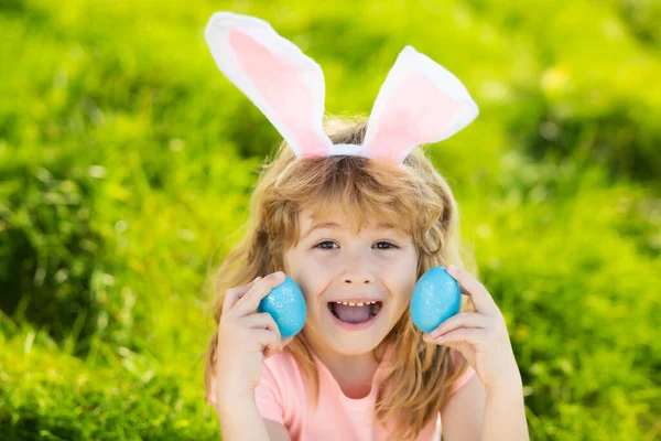 Niña conejita de Pascua. Niños cazando huevos de Pascua. Niño con huevos de Pascua y orejas de conejo en el patio trasero. Niño en traje de conejo jugar al aire libre. —  Fotos de Stock