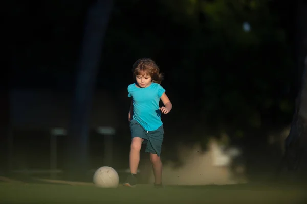 Dziecko bawiące się w piłkę na placu zabaw w parku. chłopiec dziecko kopanie piłki nożnej na boisku podczas. — Zdjęcie stockowe