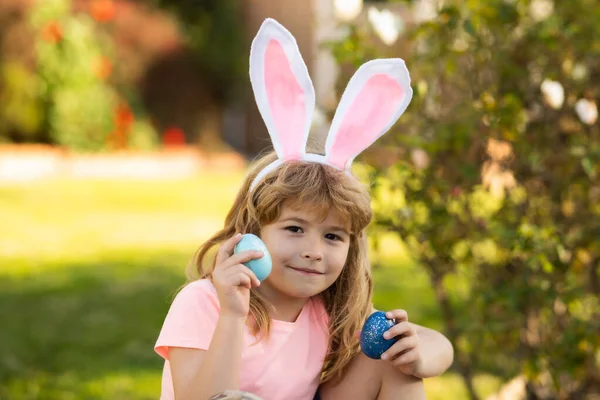 Niño cazando huevos de Pascua. Niño con huevos de Pascua y orejas de conejo al aire libre. Vacaciones de primavera. —  Fotos de Stock