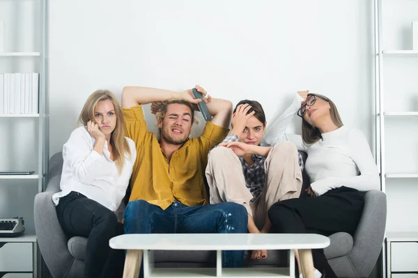 Vrienden die thuis voetbal kijken. Een groep jongeren die thuis op de bank zitten te praten. Vrienden die thuis tv kijken. — Stockfoto