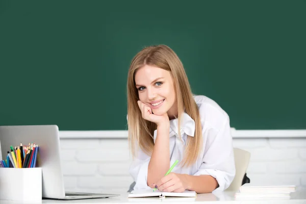 Lachende student, jonge leuke blonde vrouw online kijken webinar op laptop, luisteren leren onderwijs cursus, zitten aan het werk bureau in de klas, elearning concept. — Stockfoto