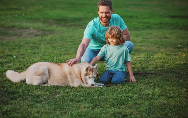 Doğada köpeği olan baba ve oğul. Evcil köpekli baba ve çocuk dışarıda eğleniyorlar. Çocuk köpekle yürüyor.. — Stok fotoğraf