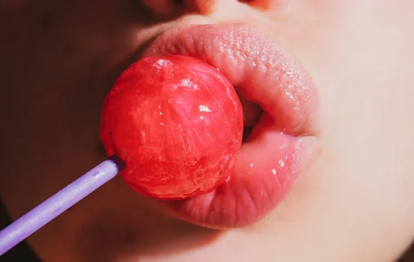 Szexi nő szája rózsaszín ajkak kezében nyalóka, szépség közelkép. A szexi csaj nyalogatja a nyalókát. Szépség csillogás koncepció, közelkép. — Stock Fotó