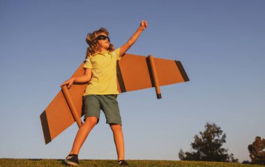 Çocukların lideri ve kazananı, başarı başlar. Heyecanlı çocuk parkta oyuncak jet kanatlı süper kahramanla oynuyor. Mavi gökyüzünde tatil gezisi.