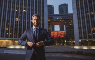 Yönetici işadamı. Modern ofis yakınlarında takım elbiseli bir CEO portresi. Şirket binasının önünde duran mutlu lider..
