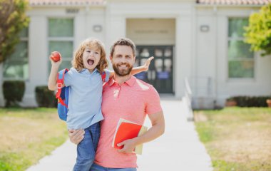 Baba oğul okul parkında yürüyorlar. Ailesi birinci sınıfta küçük bir çocuğu yönetiyor..