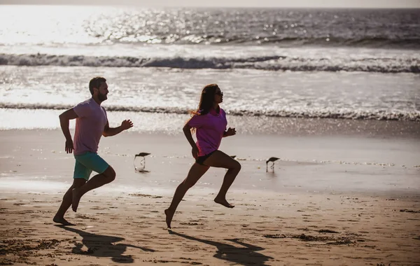 Paar läuft am Strand. Silhouette junger Männer und Frauen beim Joggen am Meer. — Stockfoto