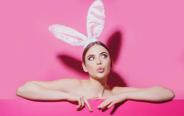 Easter young woman studio wearing bunny ears. curious isolated on pink. — Stock Photo, Image