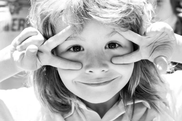Ungar roliga ansikte närbild. Begreppet barndom, fritid och barn. Glad unge som har kul och gör ansikten utomhus. Barnens dag. — Stockfoto