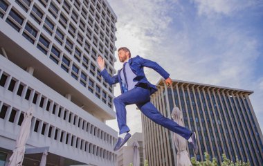 Şehir caddesinde koşan ve zıplayan bir iş adamı.