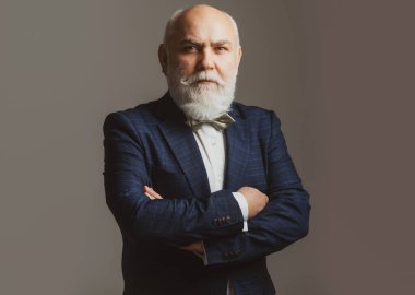 Kıdemli Takım Elbiseli Adam, 60 yaşında. Olgun iş adamı gri kameraya bakıyor..