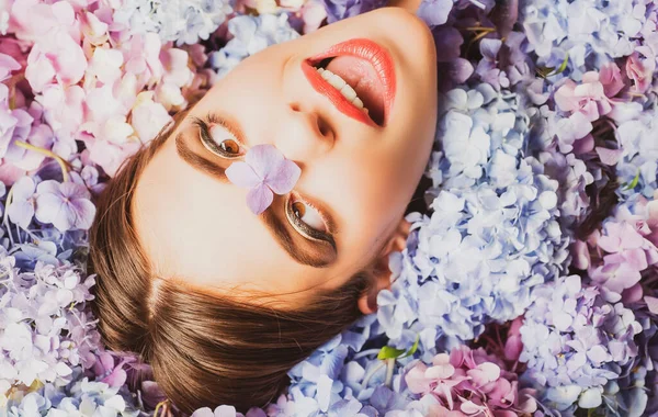 La belleza natural. Una mujer graciosa acostada sobre flores. Unidad con la naturaleza. Blossom. Maquillaje cosmético y cuidado de la piel. Chica con flores de hortensias. — Foto de Stock