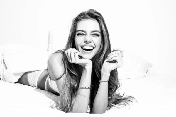 Vacker leende flicka som har roligt i sängen. Lycklig flicka skrattar i sovrummet, ler glatt. — Stockfoto