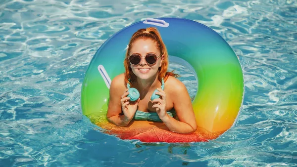 Yaz tatili. Güneşlenmenin tadını çıkarıyorum. Mayo giymiş bir kadın havuz kulaklığında şişirilebilir bir çemberde müzik dinliyor.. — Stok fotoğraf