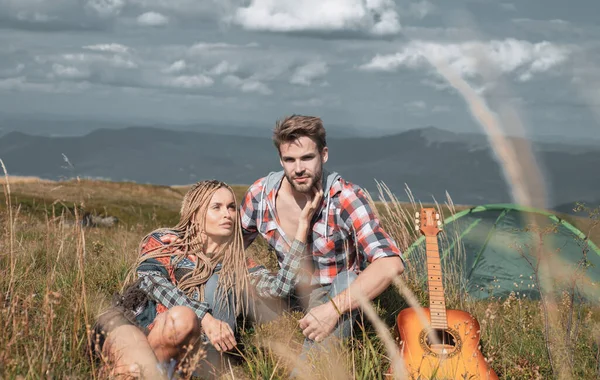 幸せなカップルの観光客の男女は、キャンプ、ギター、晴れた日の横に休息を持っています。放浪者の景色を楽しむ旅行カップル、山の背景で友人の興奮. — ストック写真