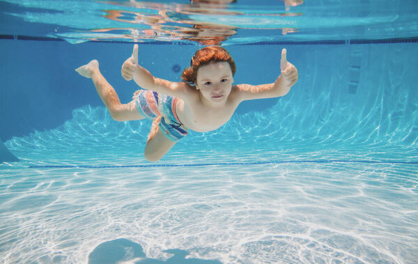 Underwater kid swim under water. Child boy swimming and diving underwater in pool. Summer family summer vacation with children. Underwater kids activity.