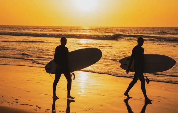 Plage tropicale océan de mer avec coucher ou lever du soleil pour les vacances d'été. Silhouette de surfeurs portant leur planche de surf sur la plage du coucher du soleil. Paysage marin océanique. — Photo